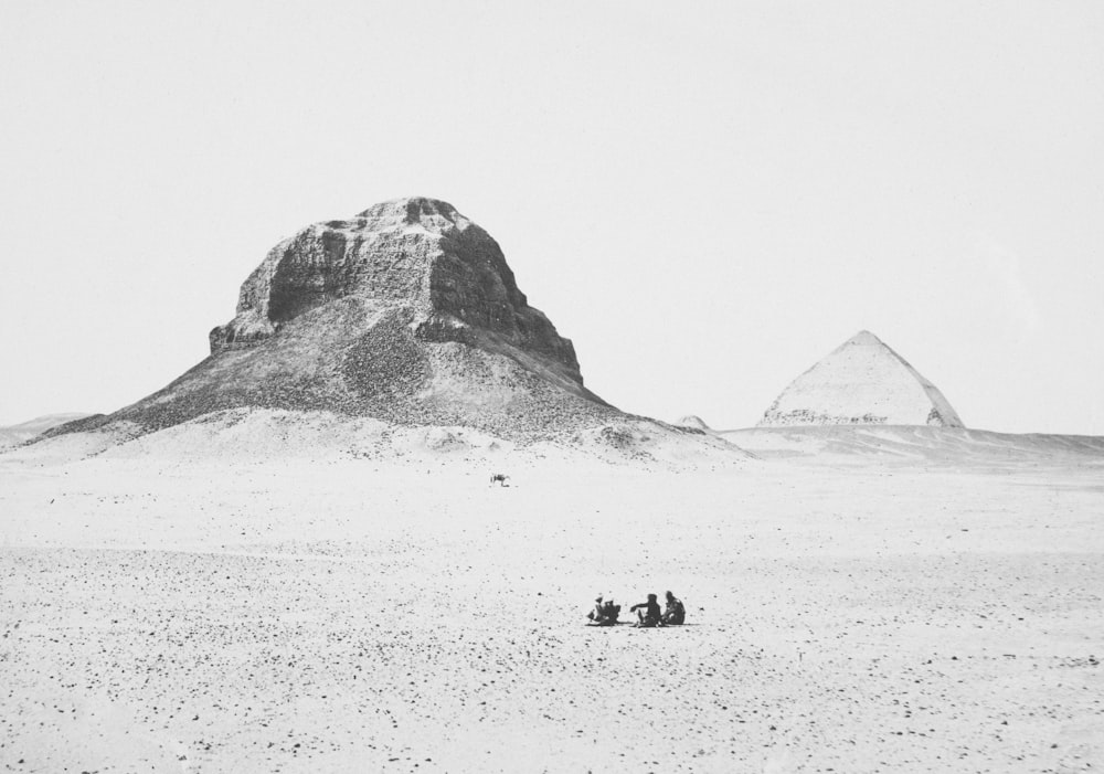 a black and white photo of people sitting in the desert