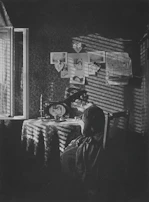 A black-and-white shot of Gwen writing lyrics in a softly lit room, surrounded by shadows and gold accents.