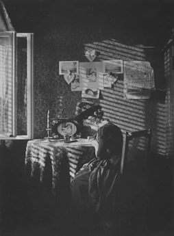 Softly lit photo of a woman journaling by a window with warm beige tones.