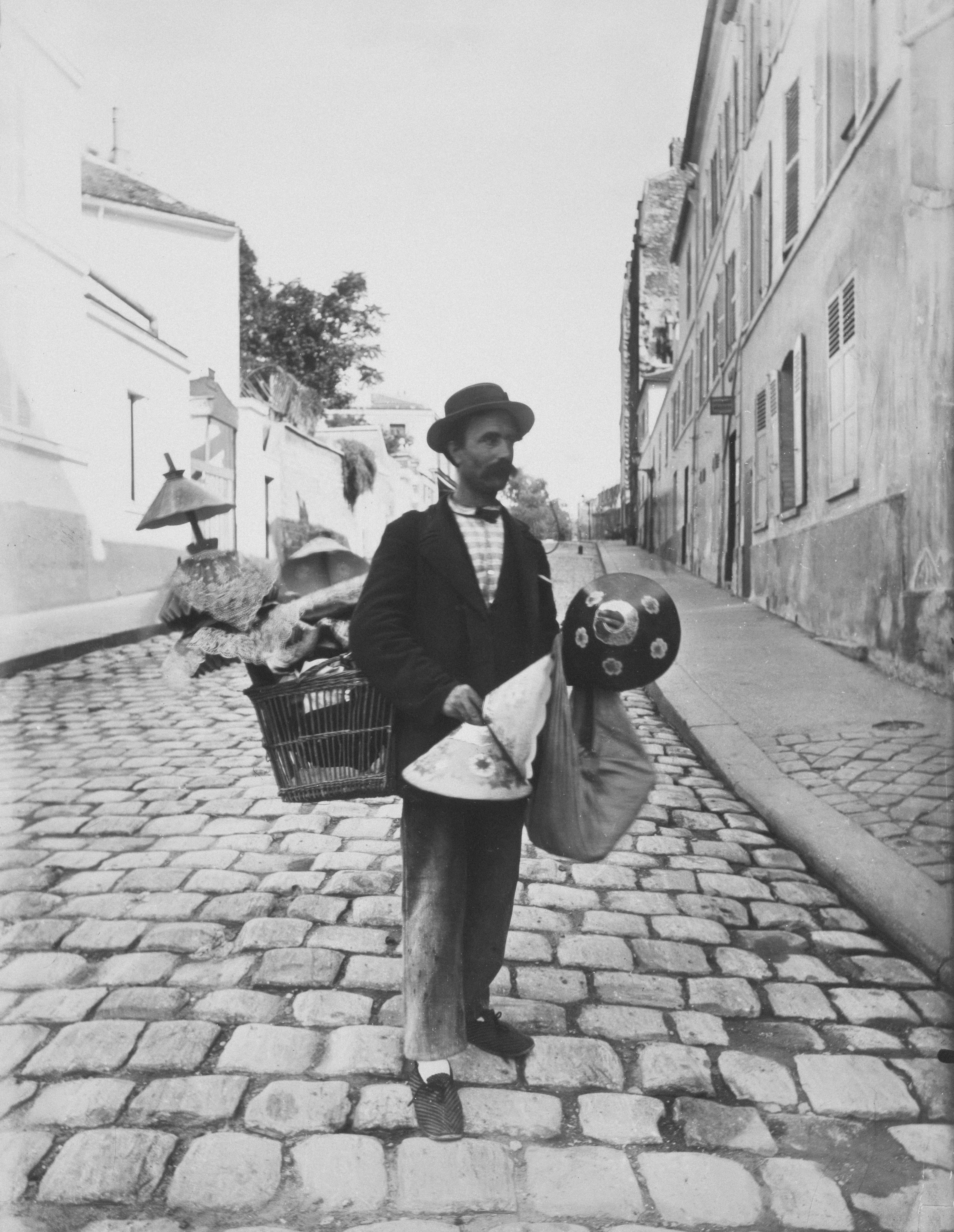 a man walking down a cobblestone street carrying a basket