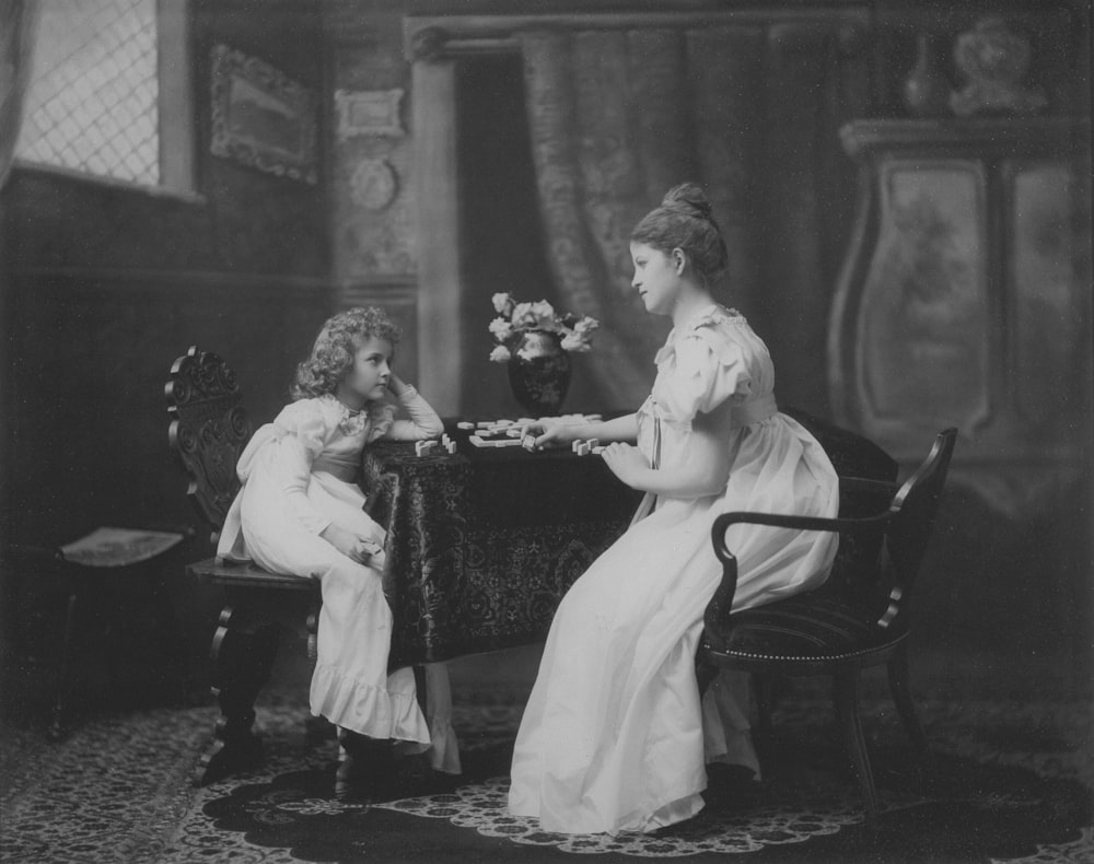 a black and white photo of two women sitting at a table