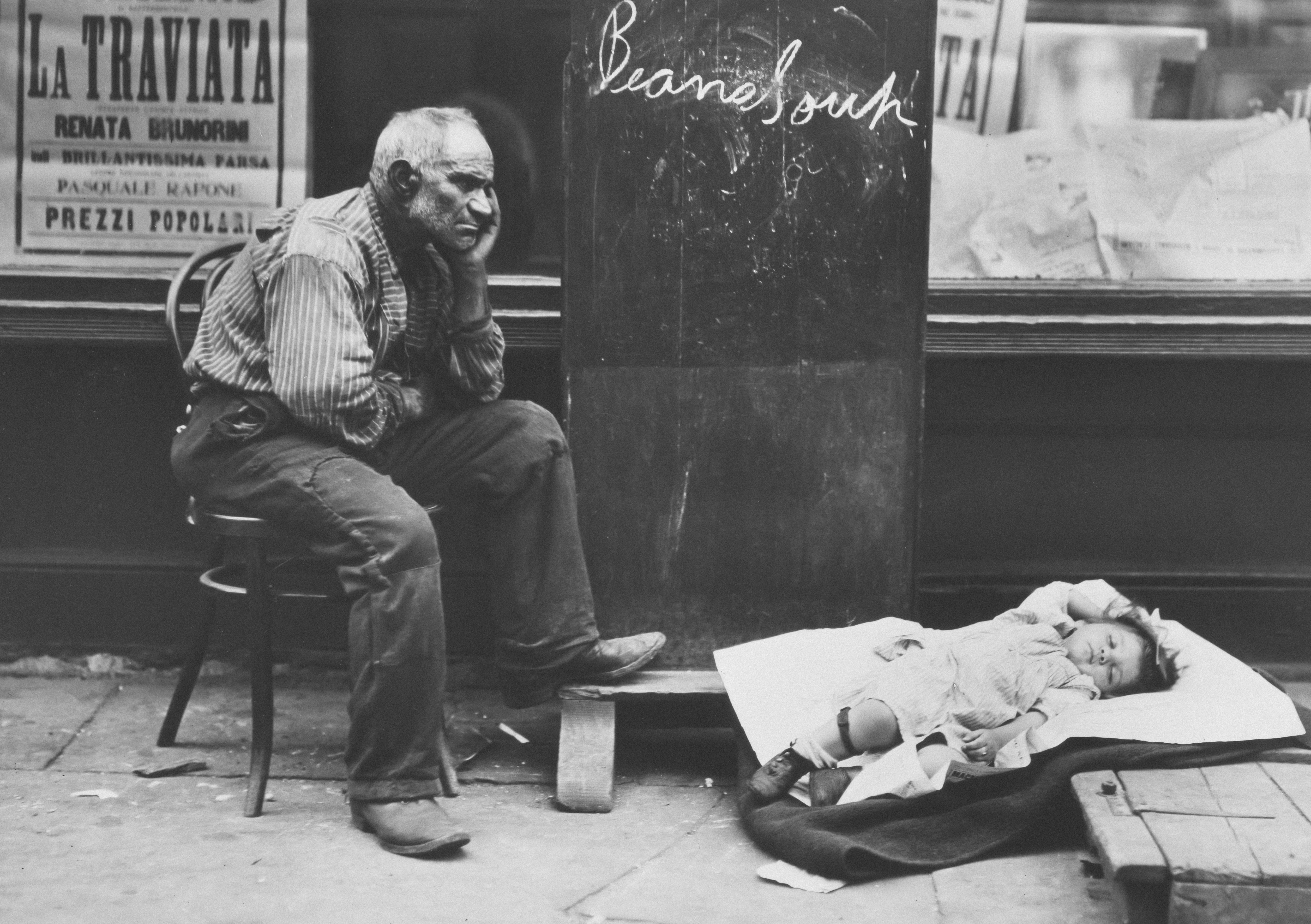 a man sitting on a chair next to a sleeping child