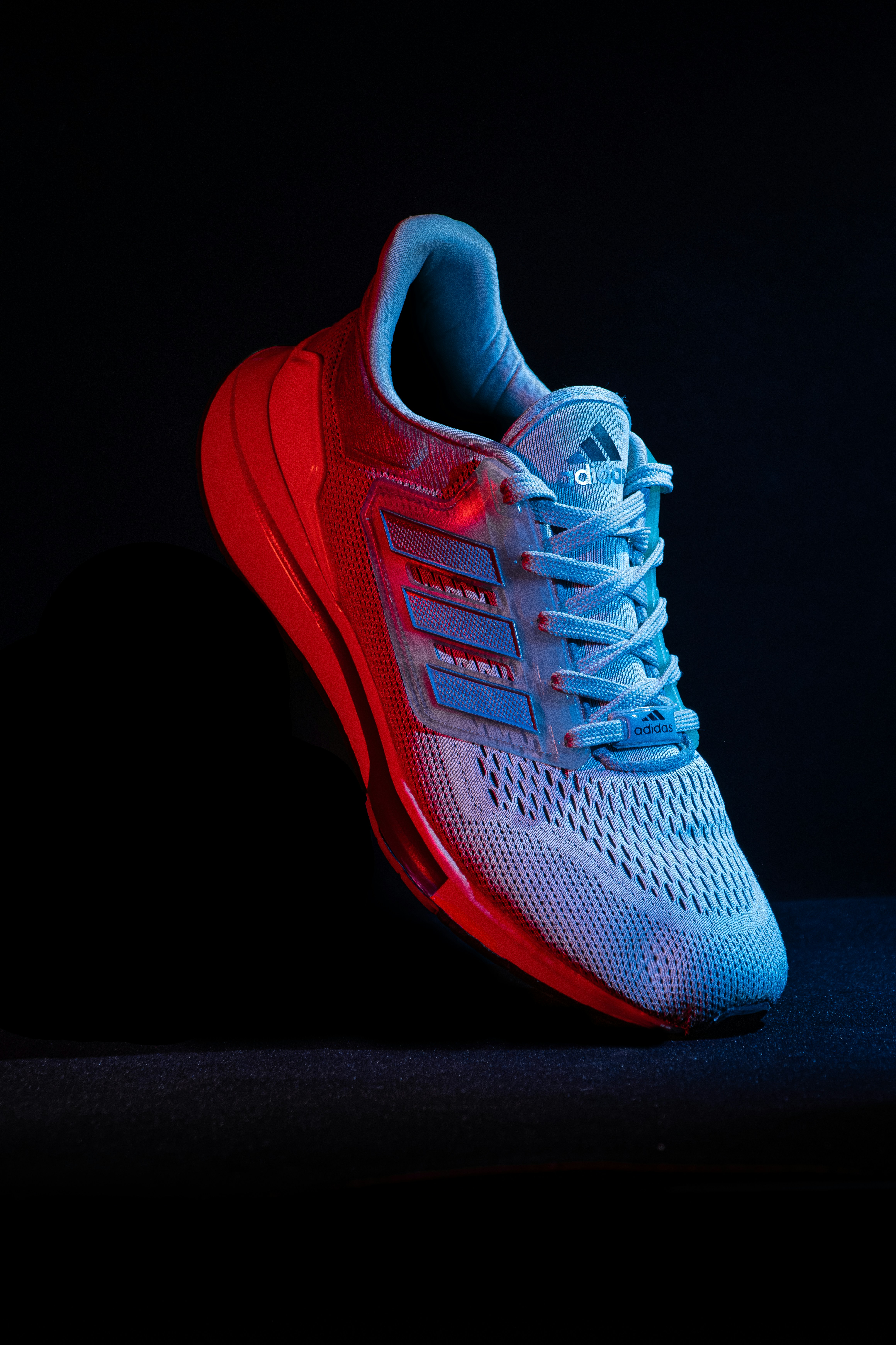 Adidas sneaker is lit with red and blue lights.