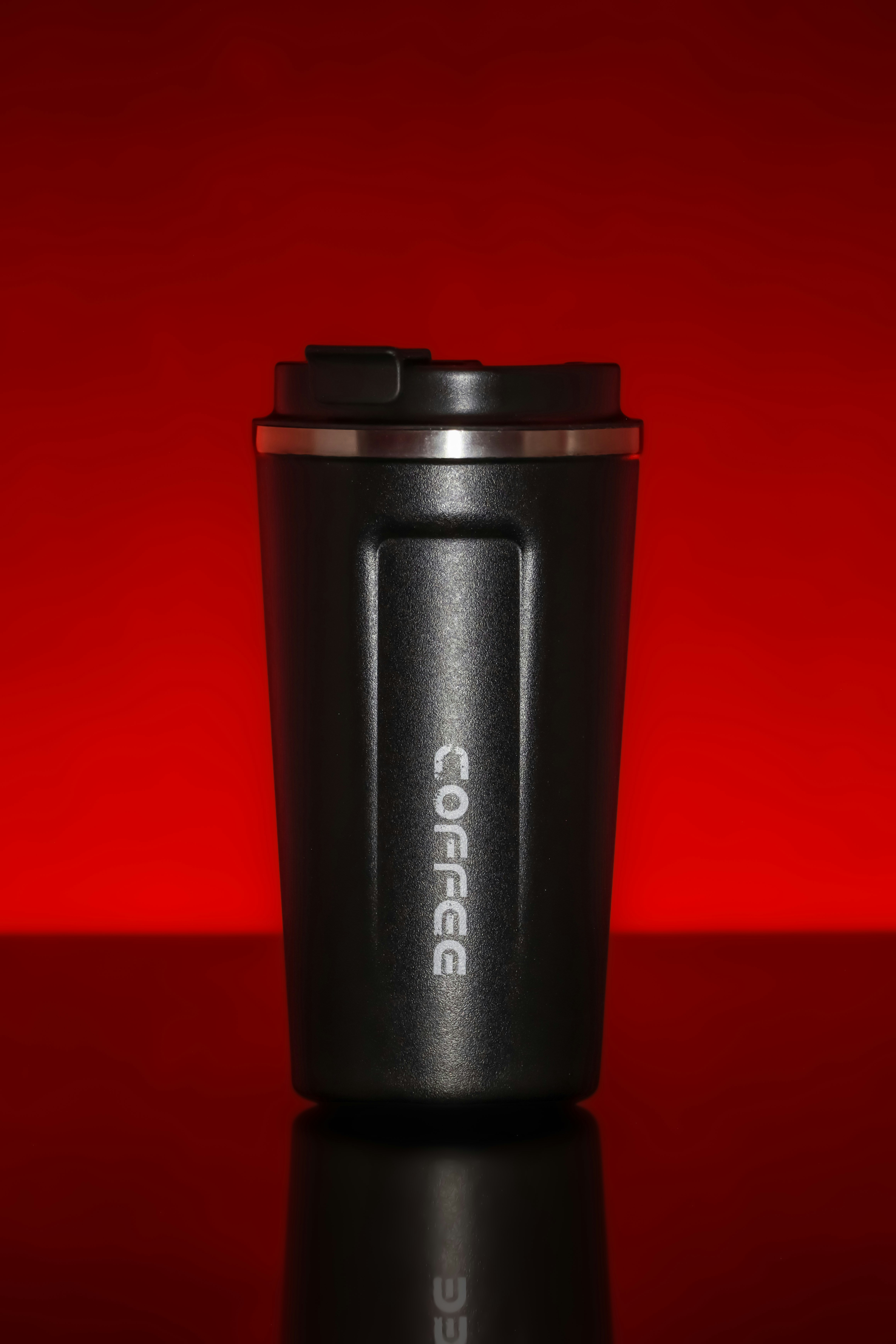 Schwarzer Kaffeebecher auf rotem Hintergrund.