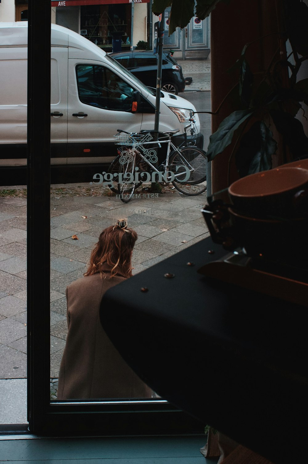 a woman looking out a window at a white van