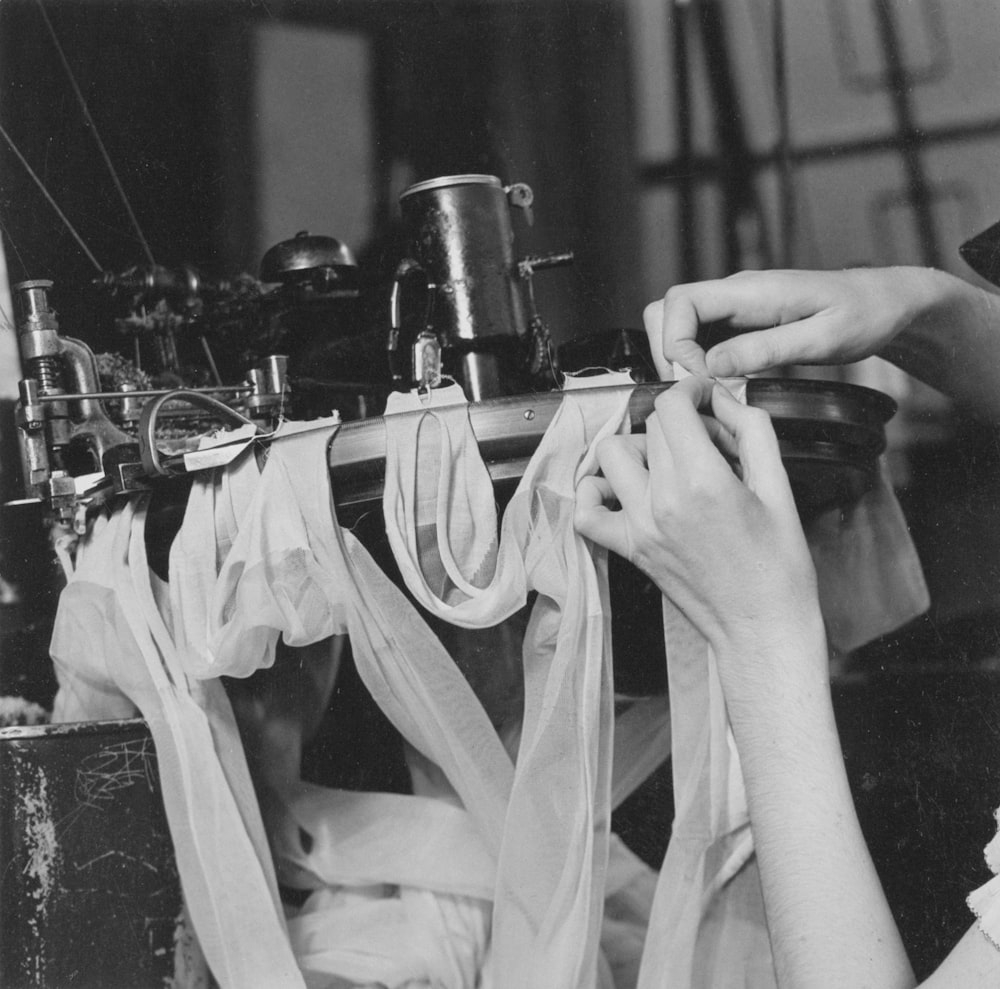 a black and white photo of a woman working on a sewing machine