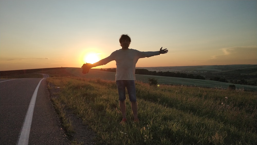 Un hombre parado al costado de una carretera al atardecer