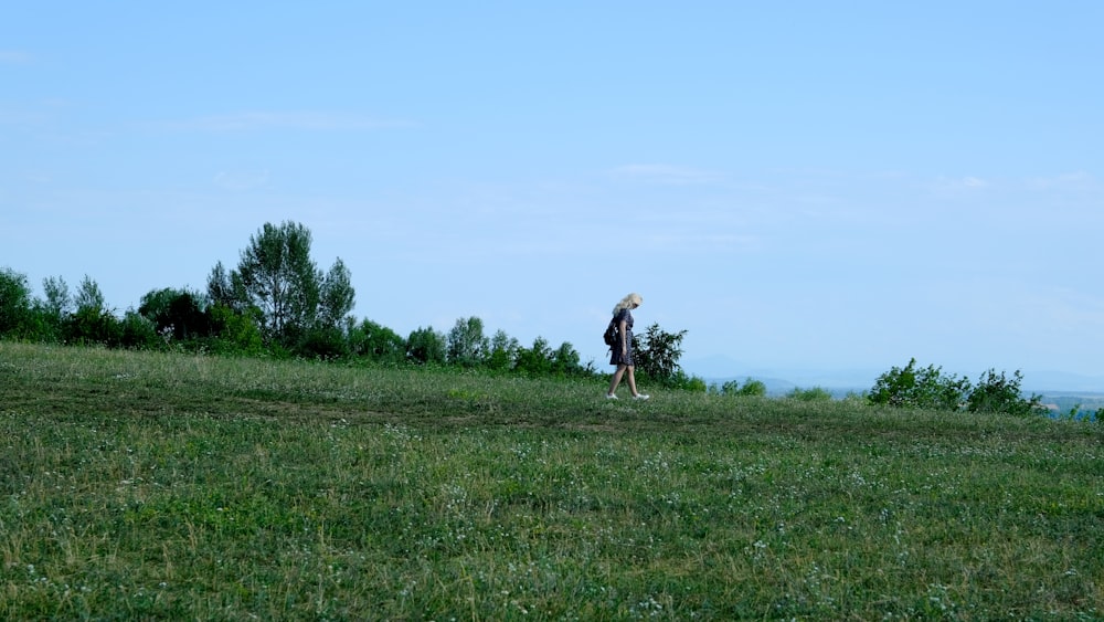 uma mulher em pé no topo de uma colina verde exuberante
