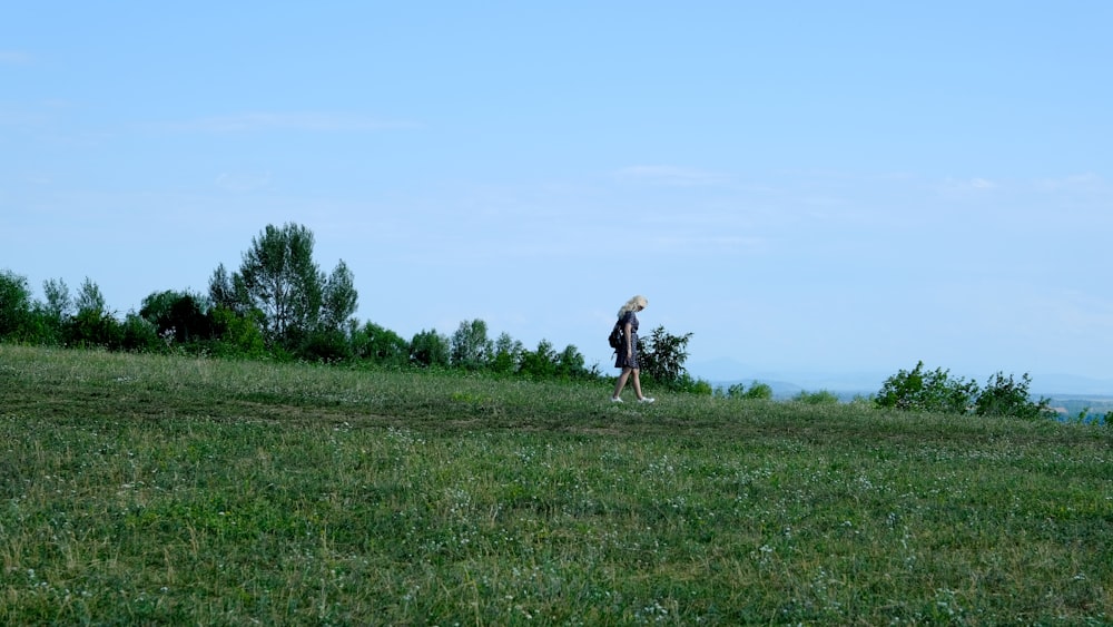 a woman standing on top of a lush green hillside