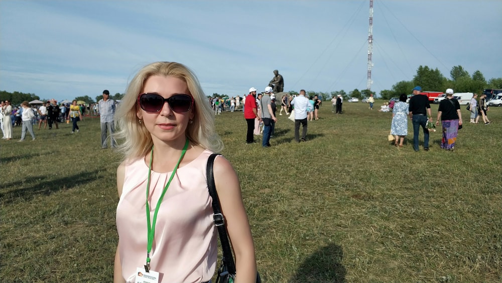 a woman wearing sunglasses standing in a field