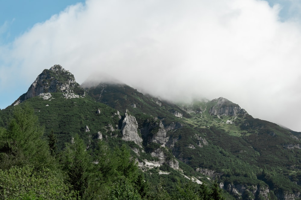 Ein sehr hoher, mit Wolken und Bäumen bedeckter Berg
