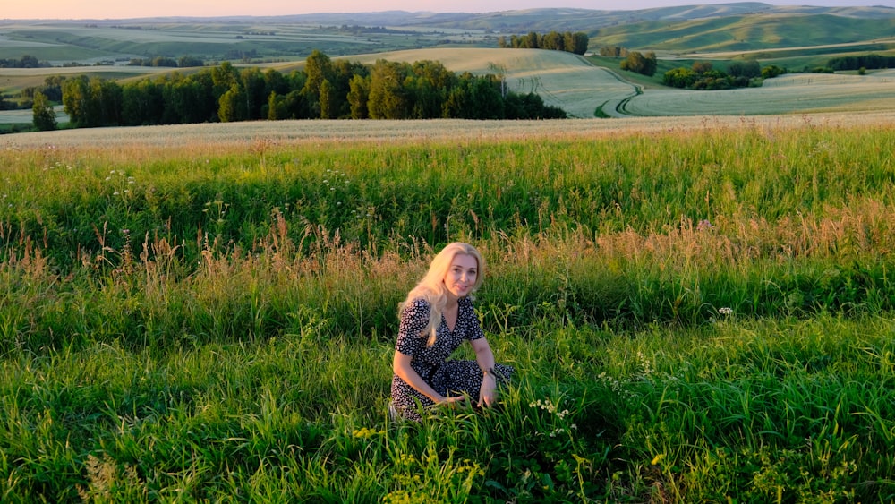 uma mulher sentada em um campo de grama alta