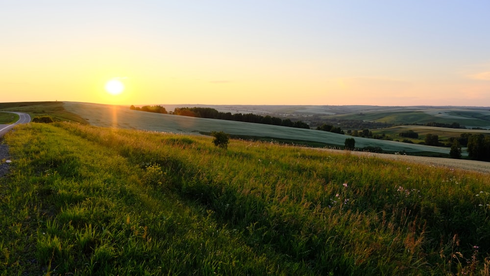 the sun is setting over the rolling hills