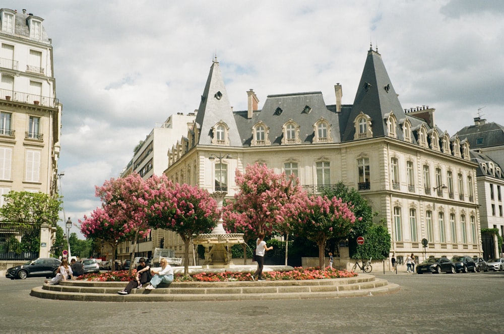 a group of people sitting around a fountain in front of a building