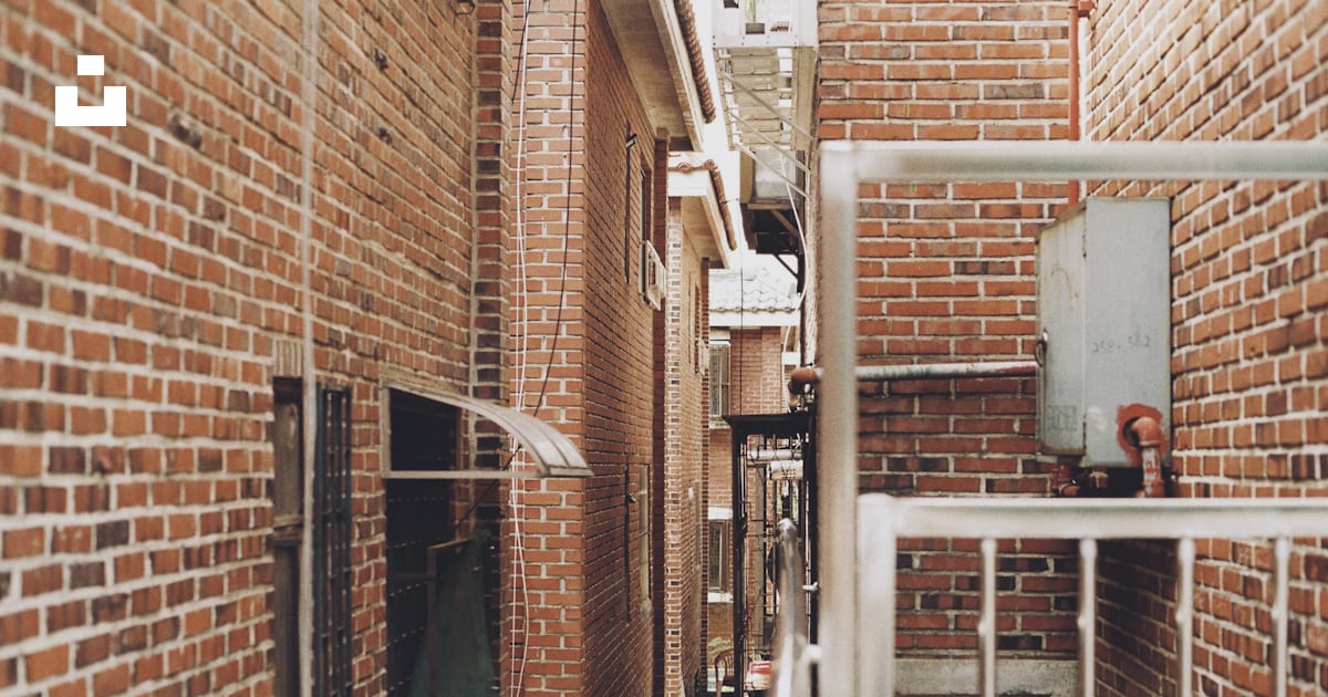 A narrow alley way with brick walls and metal railings photo – Free ...