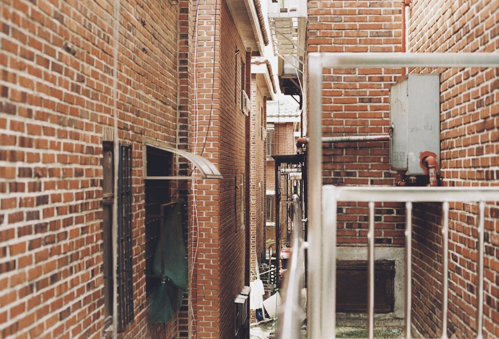 a narrow alley way with brick walls and metal railings