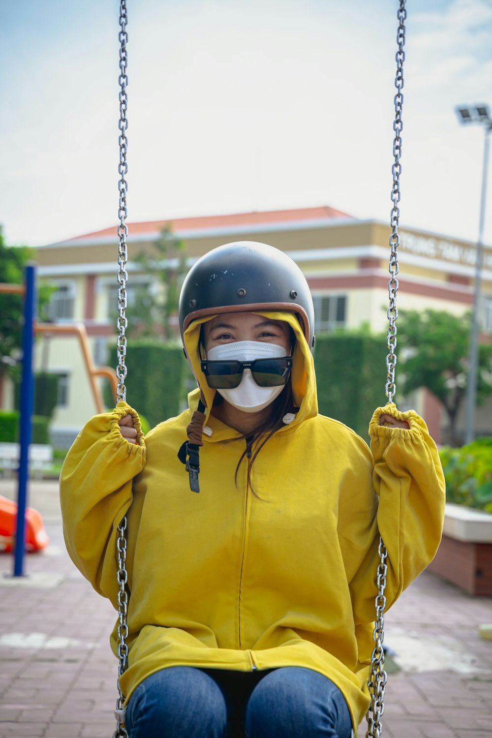 a woman in a yellow jacket and helmet on a swing