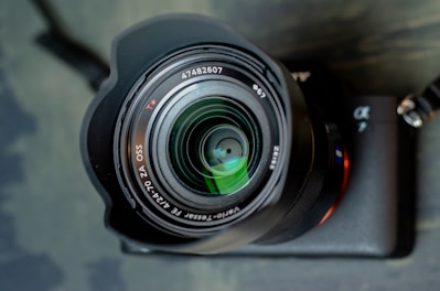 A close-up of a professional camera lens with reflections of a scenic landscape.