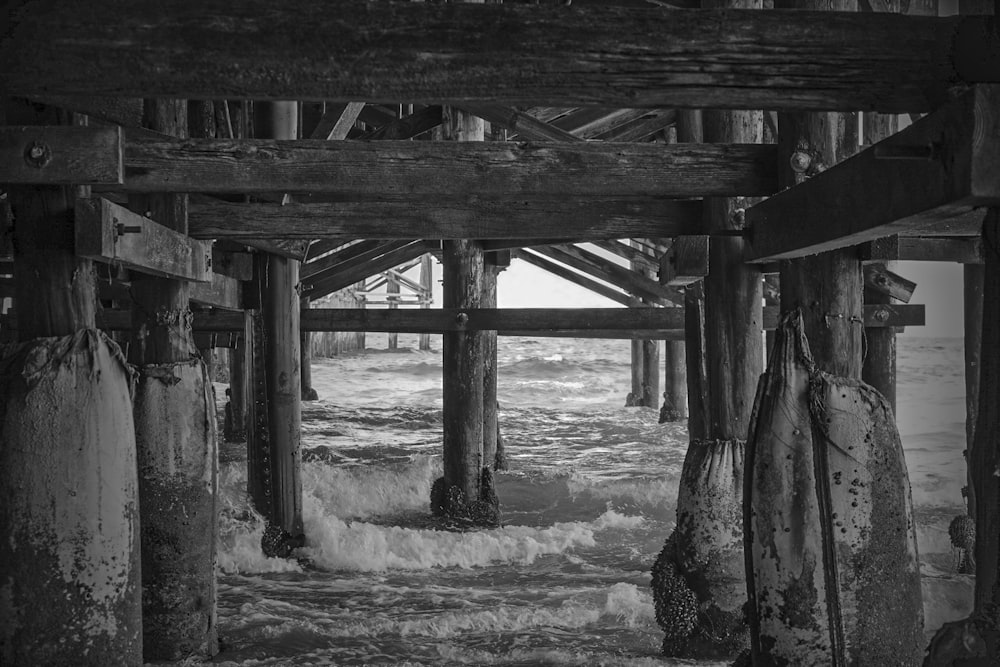 a black and white photo of the ocean under a pier