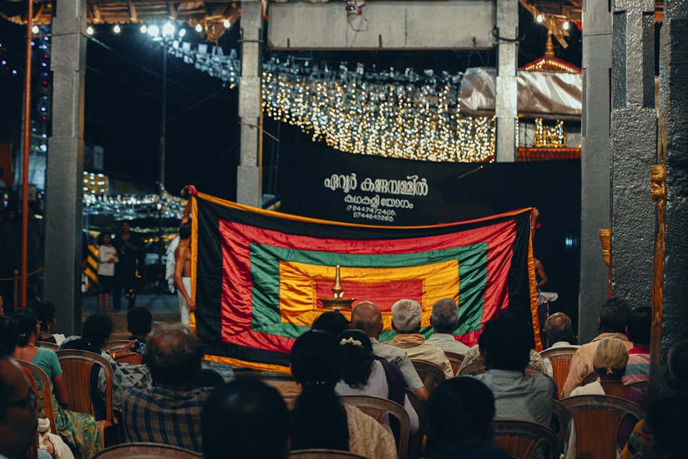 a group of people sitting in chairs in front of a flag