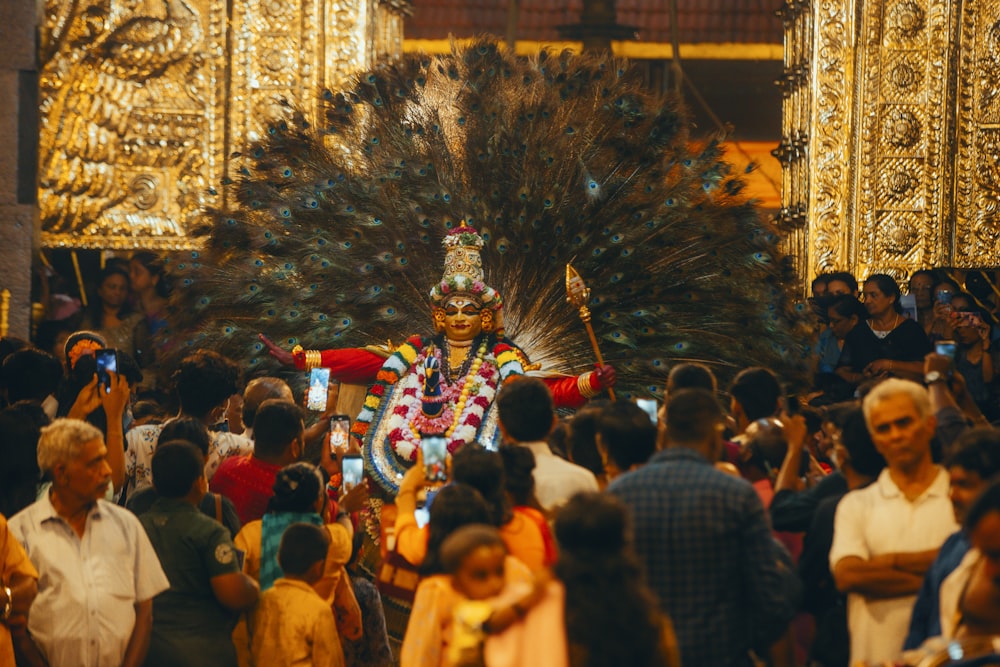 a man dressed in a costume and feathers walking through a crowd