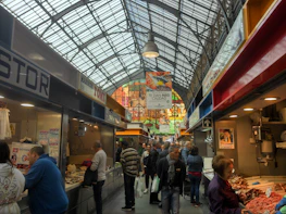 Vibrant modern food market bustling with customers and colorful stalls.