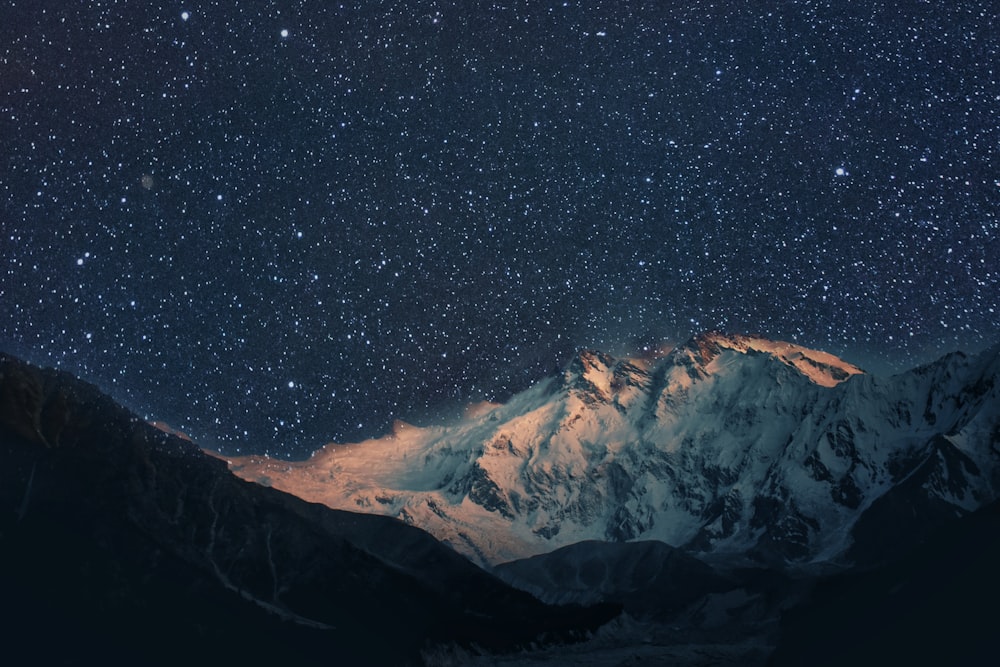 the night sky over a snowy mountain range