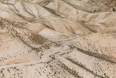 Wide shot of rugged terrain with sparse desert vegetation and a dirt road.