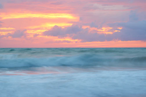 A serene, high-resolution photo capturing the gentle waves of the ocean under a soft sunset glow.