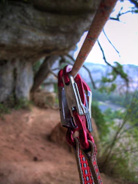 Close-up of a Singing Rock Expert III harness and Petzl Trac Plus pulley against a rugged outdoor backdrop.