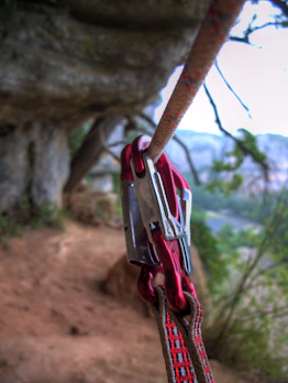 Close-up of climbing ropes and carabiners hanging on a rock wall.