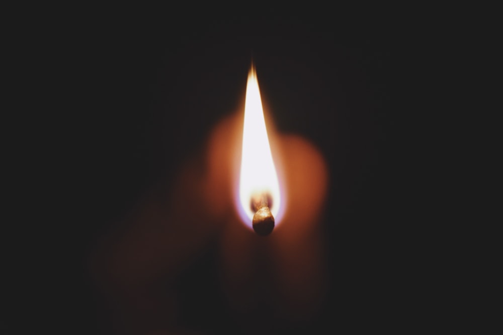 a lit matchstick in the middle of a dark room