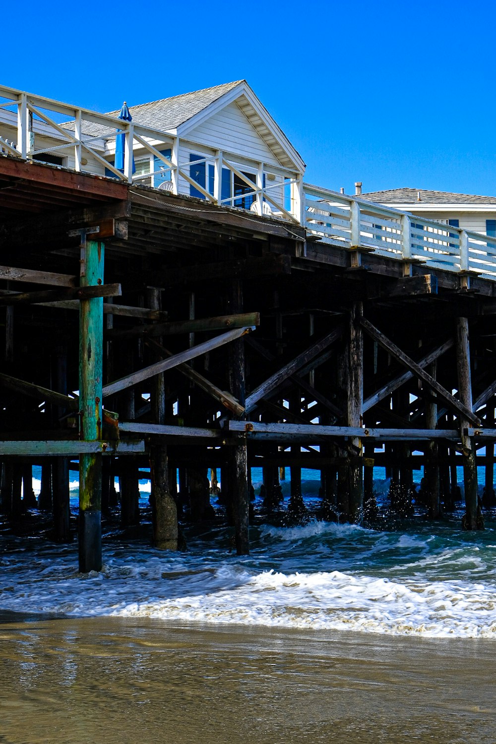 a wooden pier on the beach with waves crashing in front of it