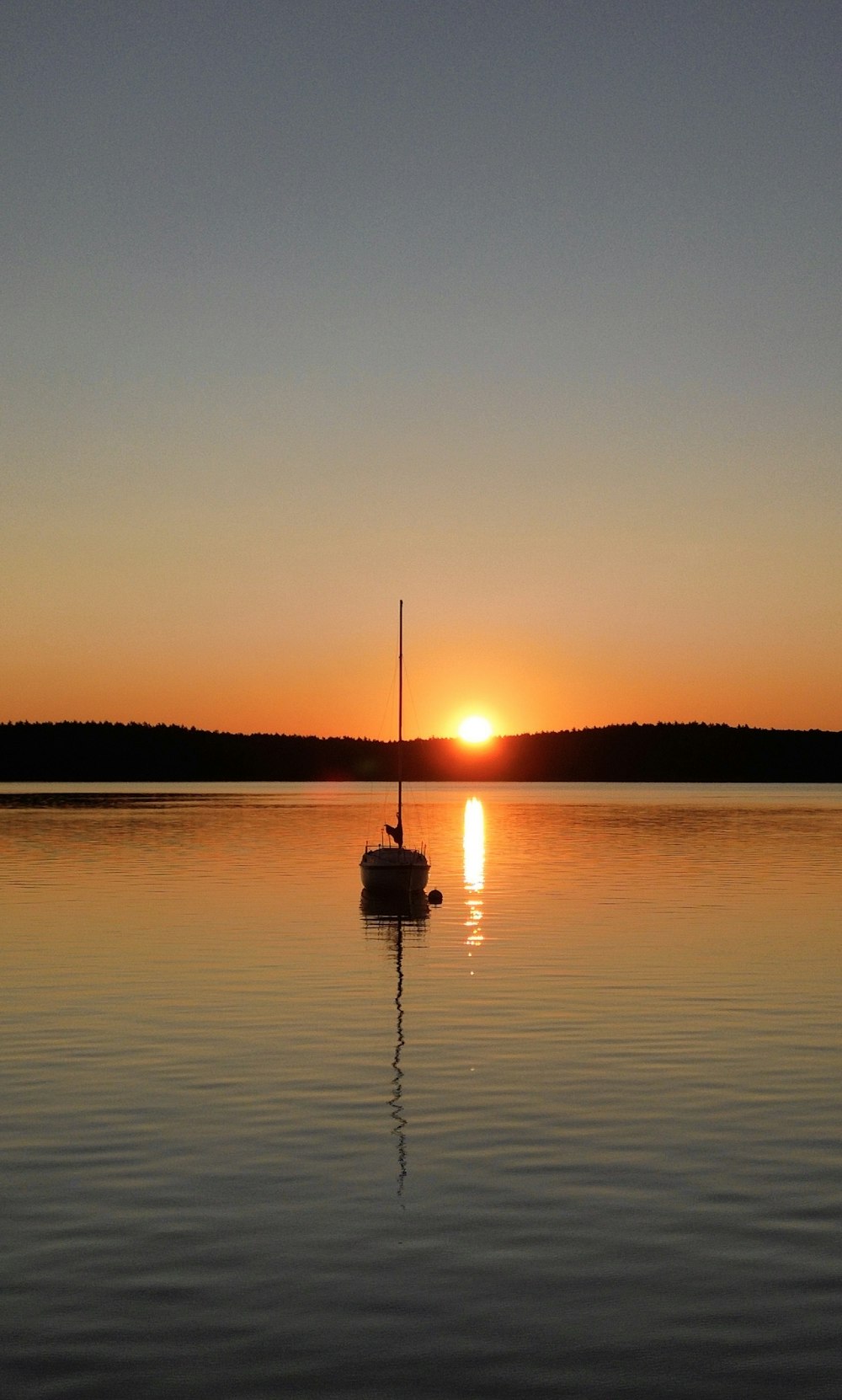 a small boat floating on top of a lake at sunset