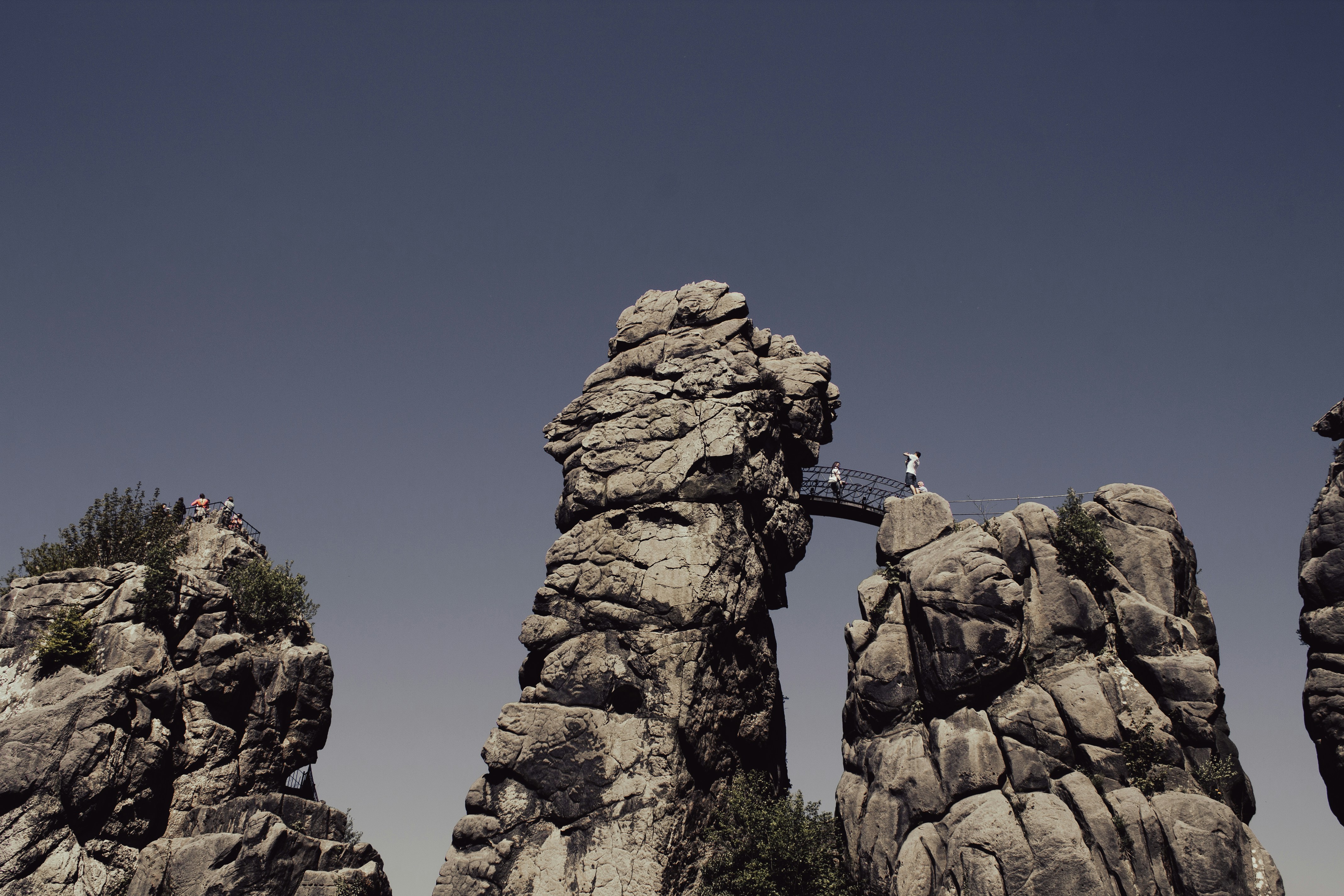 A person walking across a bridge between two large rocks photo – Free ...