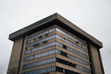 A large, multi-story concrete building with rows of windows. The architecture appears modern with an emphasis on functional design, featuring numerous small, box-like elements attached to the exterior.