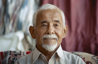 A smiling elderly man enjoying a light exercise session with a physiotherapist.