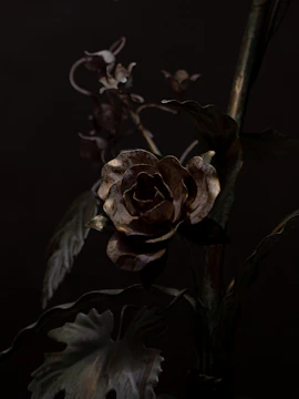 Close-up of a handmade metal rose with rustic patina against a backdrop of tools.