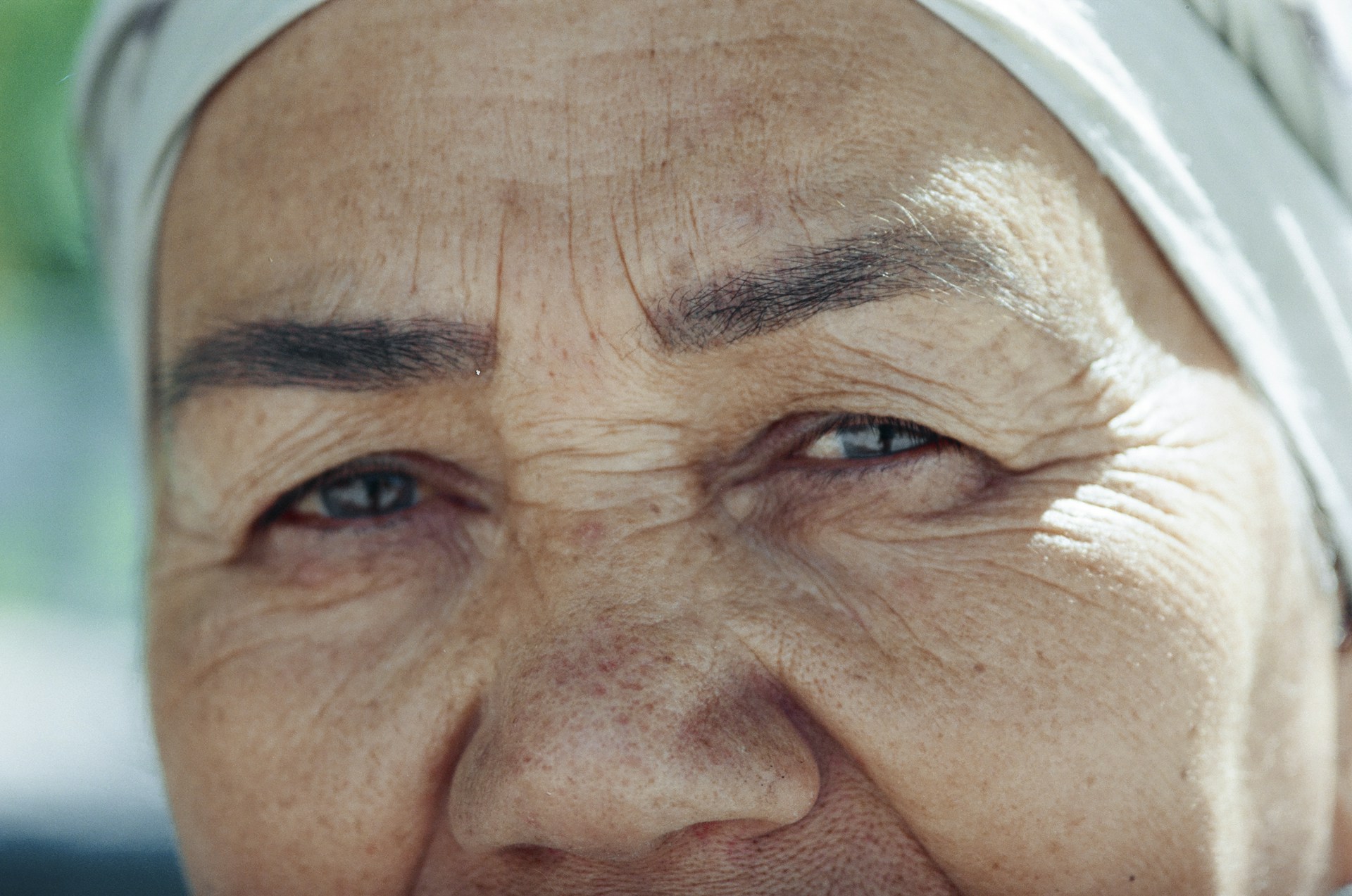 A close-up shot of an elderly woman sharing a heartfelt story, her face softly lit to highlight every wrinkle and expression.