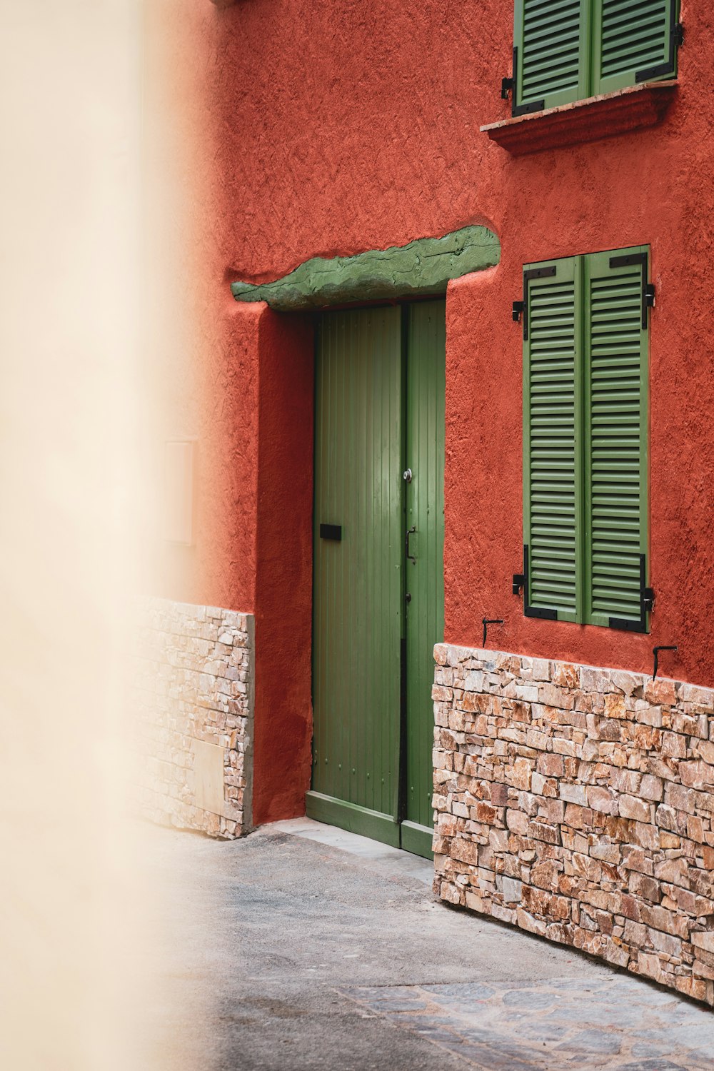 a red building with green shutters and a green door