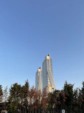 The sleek twin towers of BPTP Skynest rising above lush greenery under a clear blue sky.
