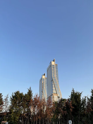 The sleek twin towers of BPTP Skynest rising above lush greenery under a clear blue sky.