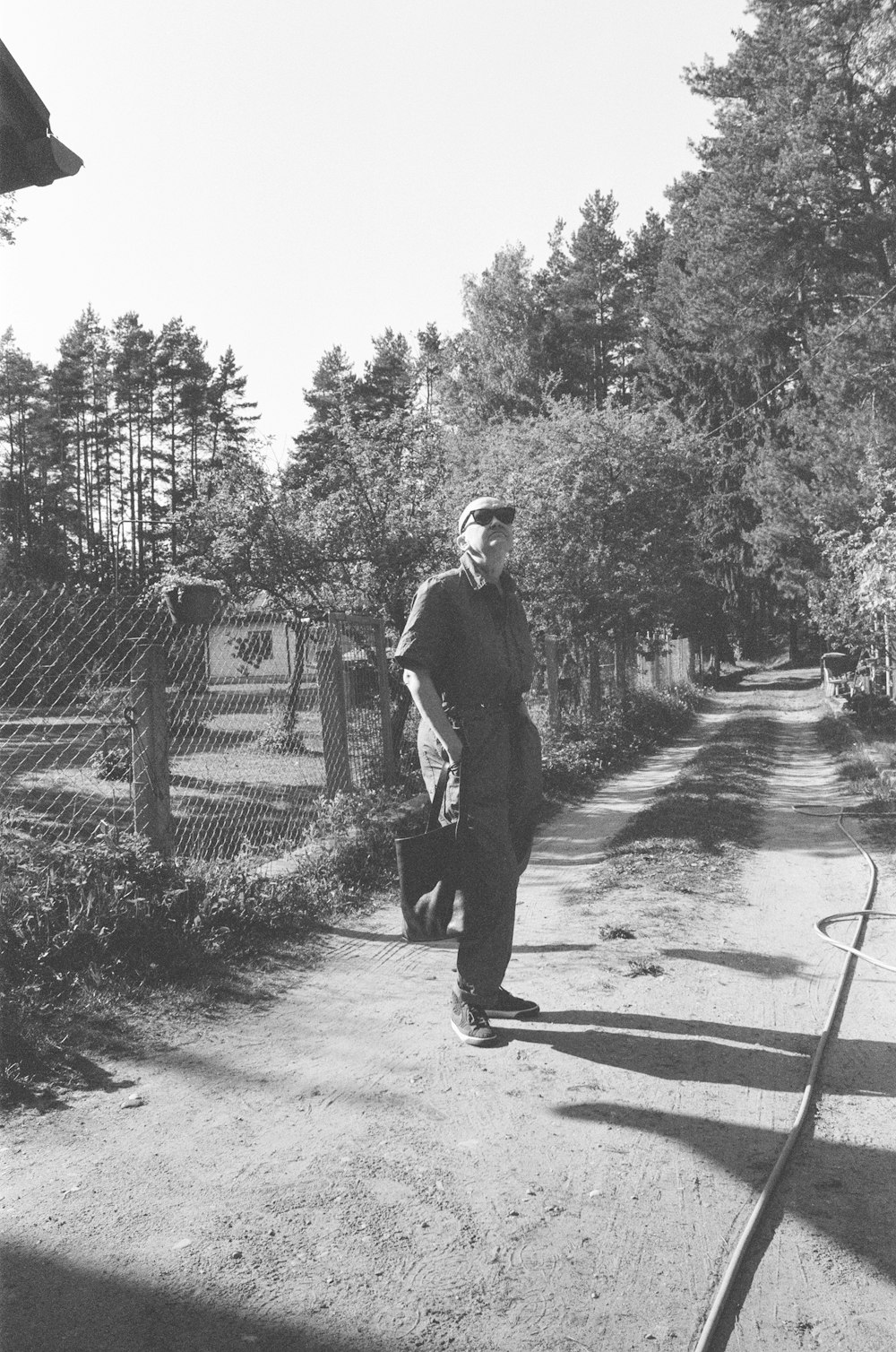 a black and white photo of a man walking down a dirt road