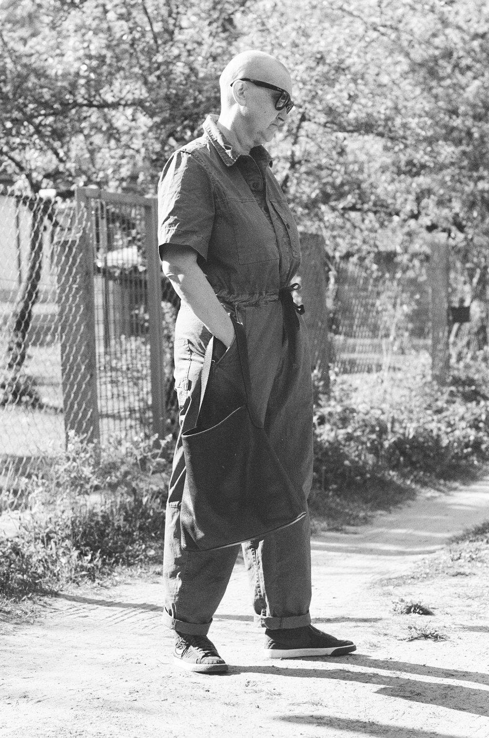 a man in overalls is standing on a sidewalk