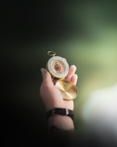 Close-up of hands holding a vintage compass over an old parchment map.