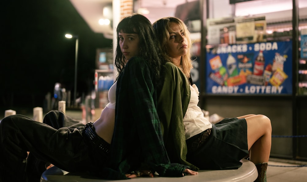 a couple of women sitting on top of a white bench