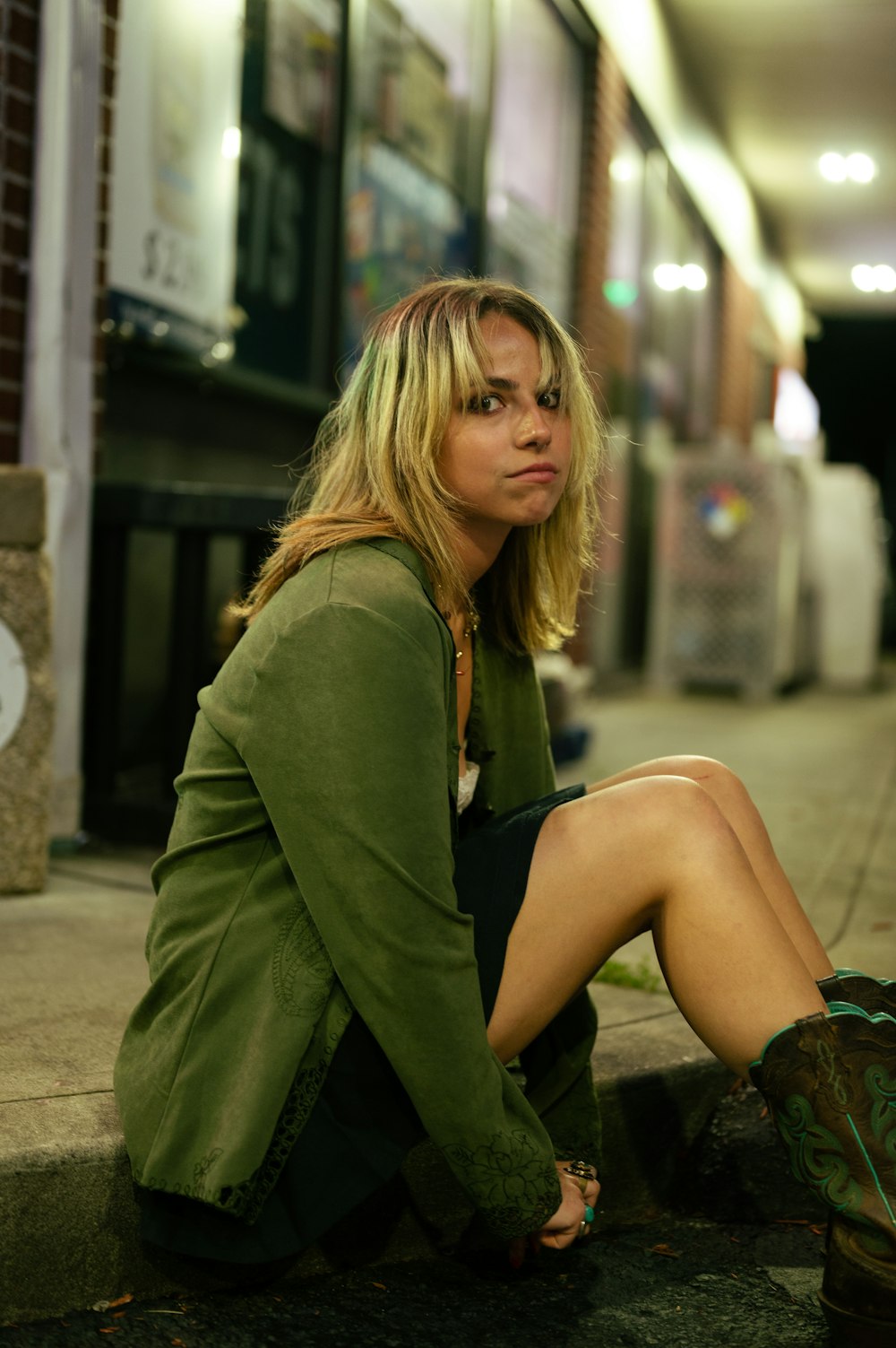 a woman sitting on the ground next to a building