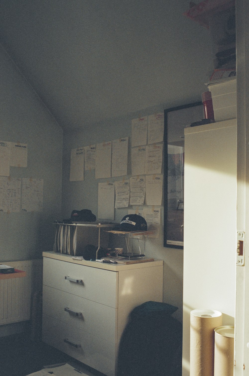 a room with a dresser and a bunch of papers on the wall