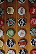 Display of various colorful caps with alcohol-themed designs on a wooden table.
