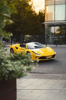 A vibrant yellow hatchback gleaming on a city street with reflections